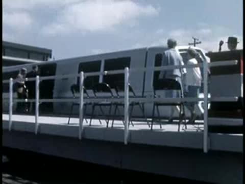 People boarding a futuristic rapid transit train on an elevated platform.