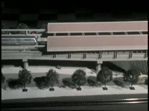 Scale model of a transit train approaching a station in a model layout.