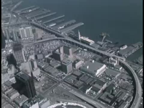 Aerial view of a coastal city with docks, bridges, and urban development.