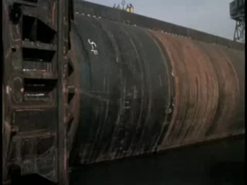 Large cylindrical metal structure near a dock or harbor area.
