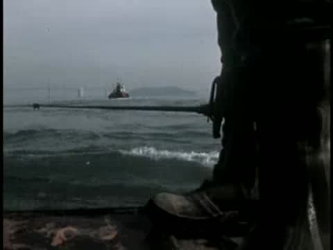 View of the water and horizon from a moving boat with a railing in the foreground.