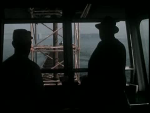 Silhouettes of two people inside a cabin looking out over the water.