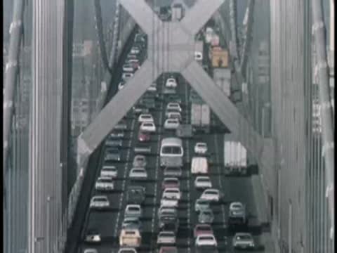 Aerial view of heavy commuter traffic flowing across a large suspension bridge.