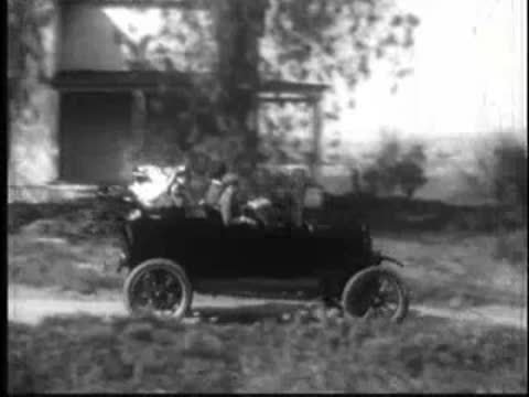 a vintage car driving along a winding rural dirt road