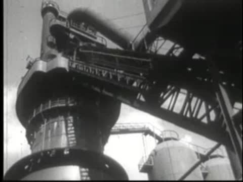 Complex industrial machinery with metal frameworks and gears operating inside a factory.