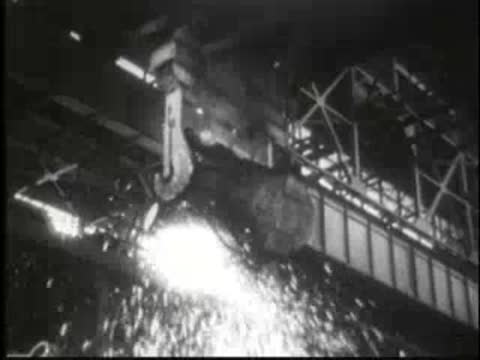 Molten metal being poured from a crane with sparks flying in a foundry.