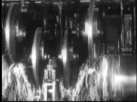 Row of spinning metal discs or wheels with fibrous material below in a factory.