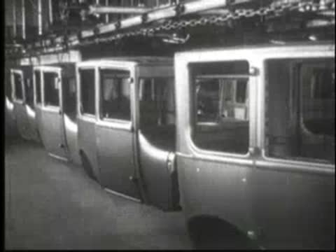 Suspended car bodies moving along an overhead conveyor in an auto factory.