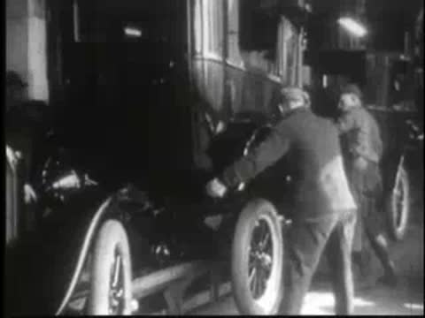 Workers assembling components on the side of a vehicle in a factory.