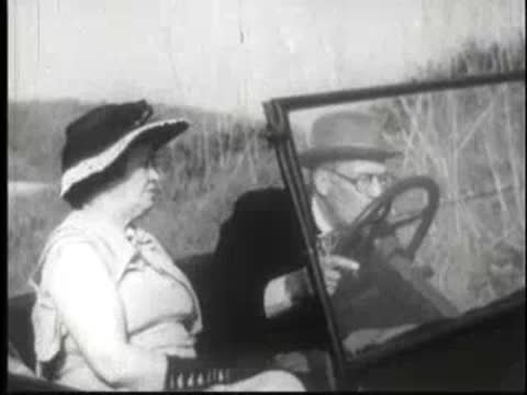 passengers and driver inside a vintage car driving along