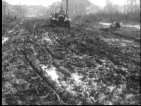 a vintage car driving through muddy terrain outdoors