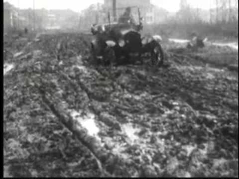 a vintage car navigating through a muddy road