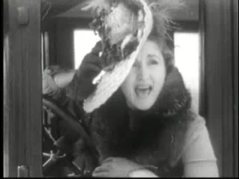 Woman in vintage car looking out with concerned expression.