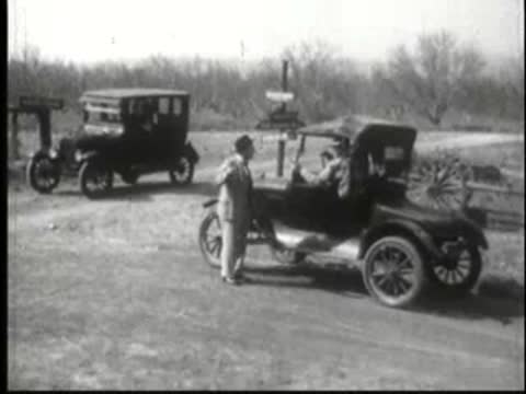 Man standing by parked vintage car in rural landscape.