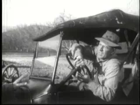 Two men conversing while sitting inside vintage automobile.