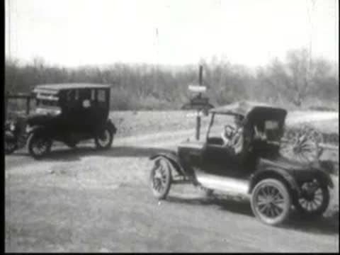 Vintage car parked by roadside with another car in distance.