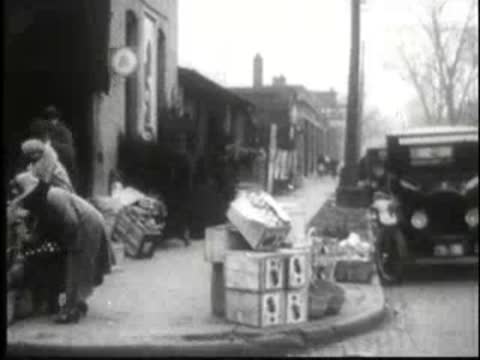 Woman loading packages into car near sidewalk shops in town.