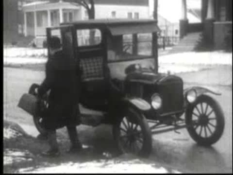 Man exiting vintage car parked in residential neighborhood street.
