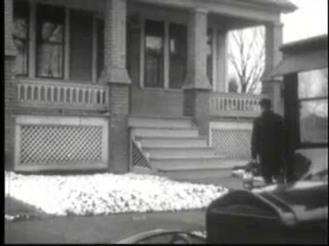 Man carrying briefcase walking up stairs to front porch of house.