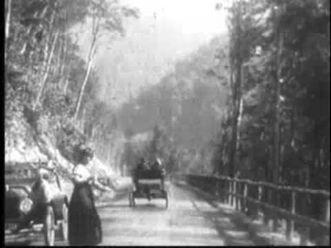 Woman standing on a mountain road while cars pass by.