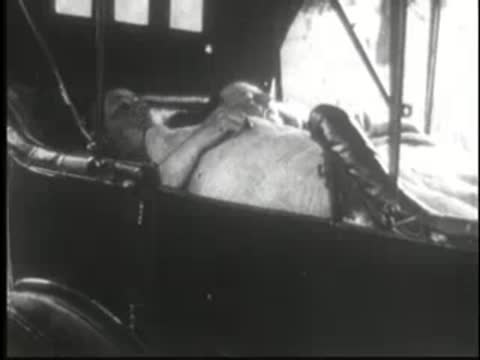 Person lying comfortably inside the back of a parked vintage car.