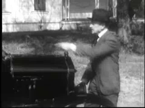 an adult cranking a car engine outdoors in daylight