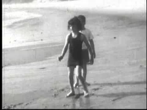 Two children playing in the sand and shallow water at the beach.