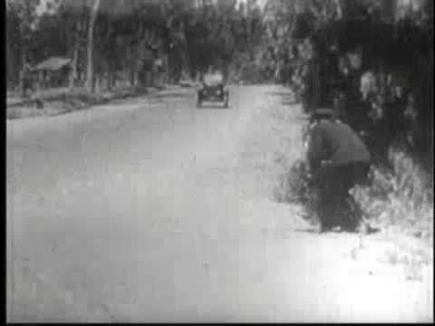 Vintage car on a large pipeline, followed by a police officer running.