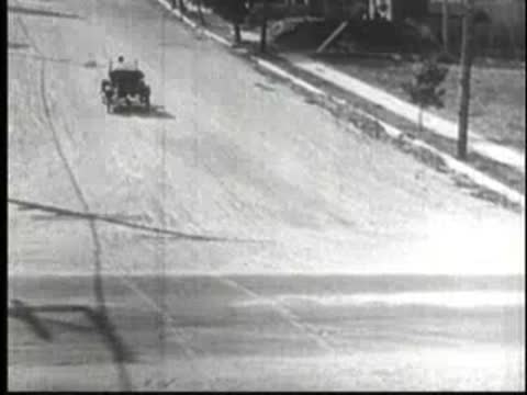 Vintage car driving fast along a suburban street.