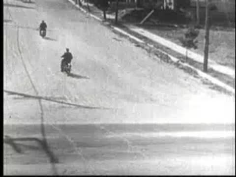 Motorcycles speeding down a suburban street during a chase.