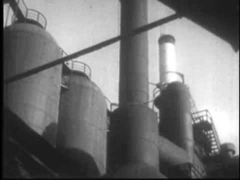 Industrial structures and large tanks seen from a low angle with a diagonal beam.