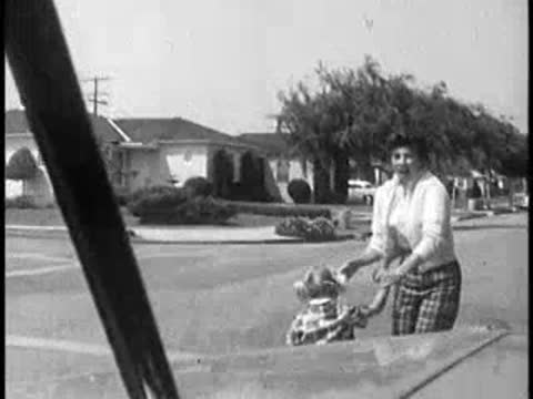 Driver's POV of mother and child on bicycle nearly hit by car, 1960s