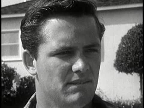 Driver looking forward with concerned expression outdoors, vintage setting, 1960s