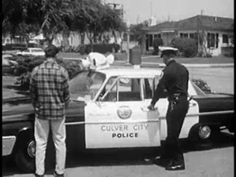 Police officer opening the door of a Culver City police car.