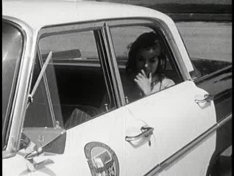 Young woman sitting inside the backseat of a police car.