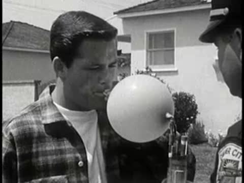 Young man blowing into a breath testing device outdoors.