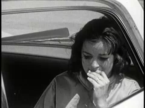 Distressed young woman sitting inside a police car.