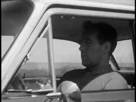 Driver profile view inside a moving car, vintage educational film.