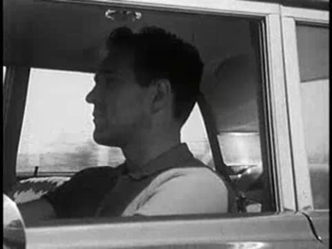 Driver side profile view inside a car, vintage educational film.
