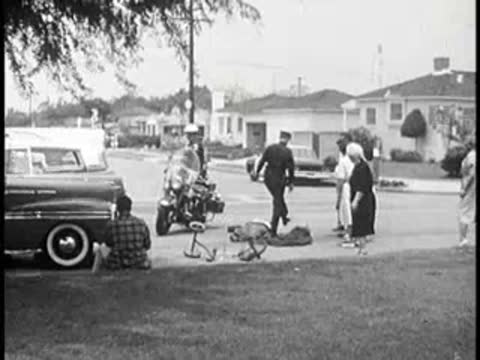 Street scene with police motorcycles, cars, and a crowd.