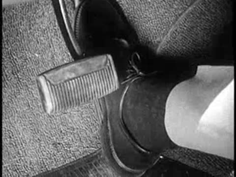 Close-up of a driver's foot pressing the brake pedal in a car, vintage educational film.
