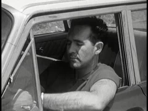 Driver looking troubled while sitting inside a car, vintage educational film.