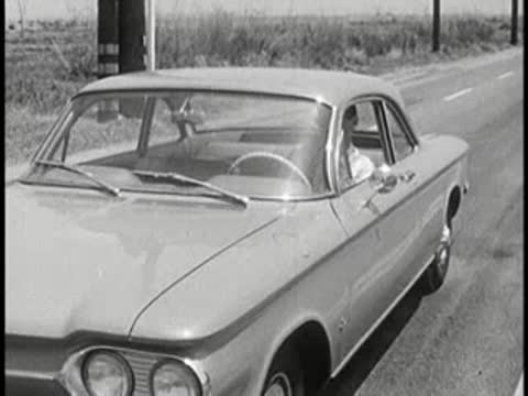 A classic car driving on an open road, vintage educational film.