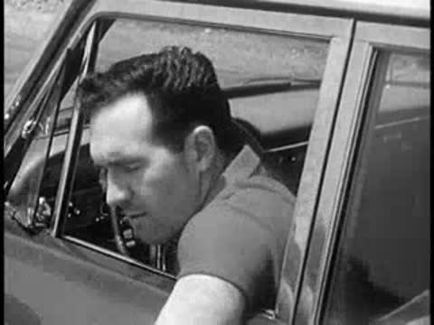 Driver looking around anxiously while sitting in a car, vintage educational film.