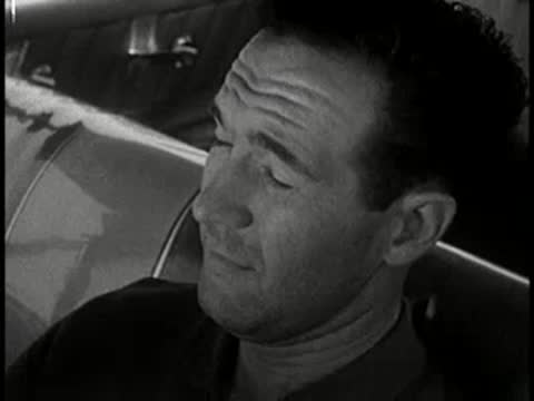 driver blinks and looks around in car interior, 1960s
