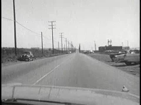 daytime driving view on straight road between fields, 1960s