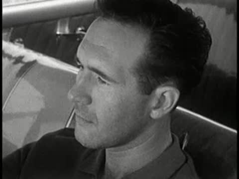 driver looking intently to the side inside car, 1960s