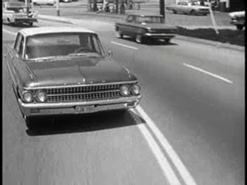 daytime view of vintage car driving on road, 1960s