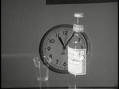 clock and beer bottle on tabletop indoors, 1960s