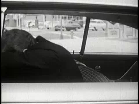 Sleeping driver slumped over steering wheel inside a moving car.